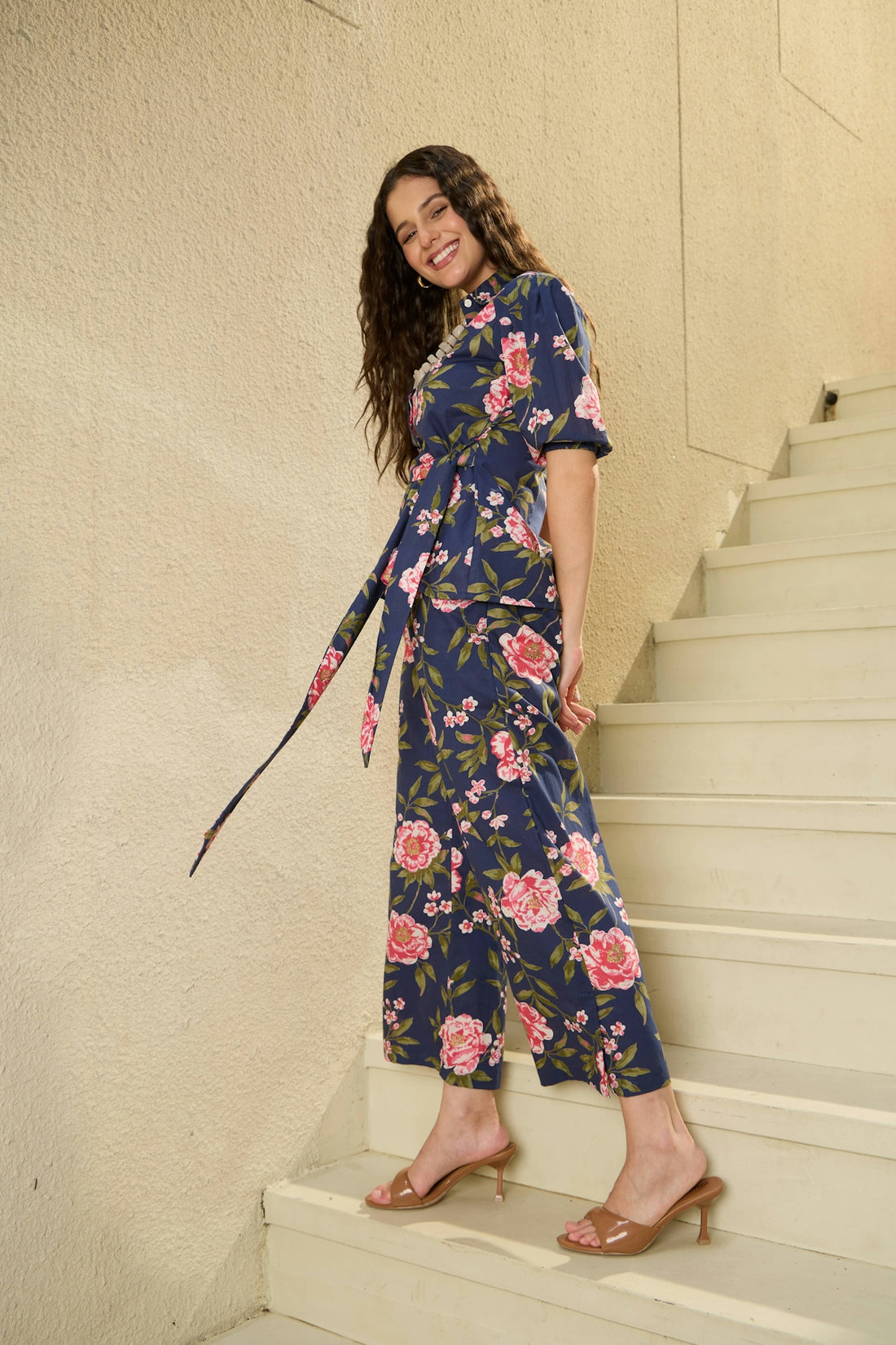 Young woman in floral jumpsuit on stairs