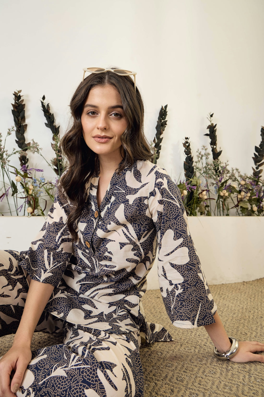 Woman in floral patterned pajamas sitting on floor