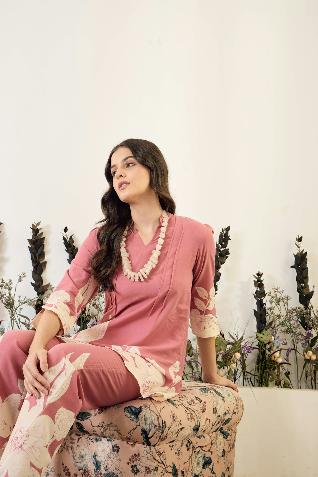 Woman in pink floral outfit sitting on patterned stool