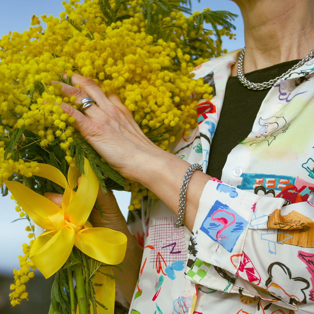 Woman holding a bright yellow mimosa bouquet with ribbon