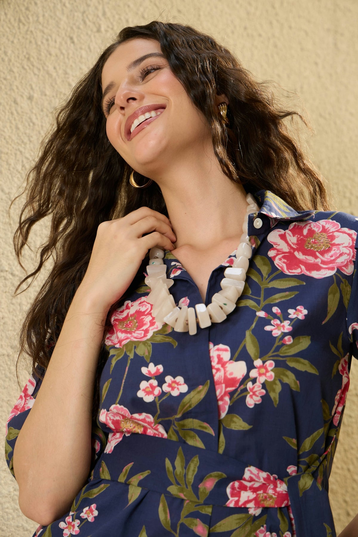 A smiling woman with a floral dress and necklace