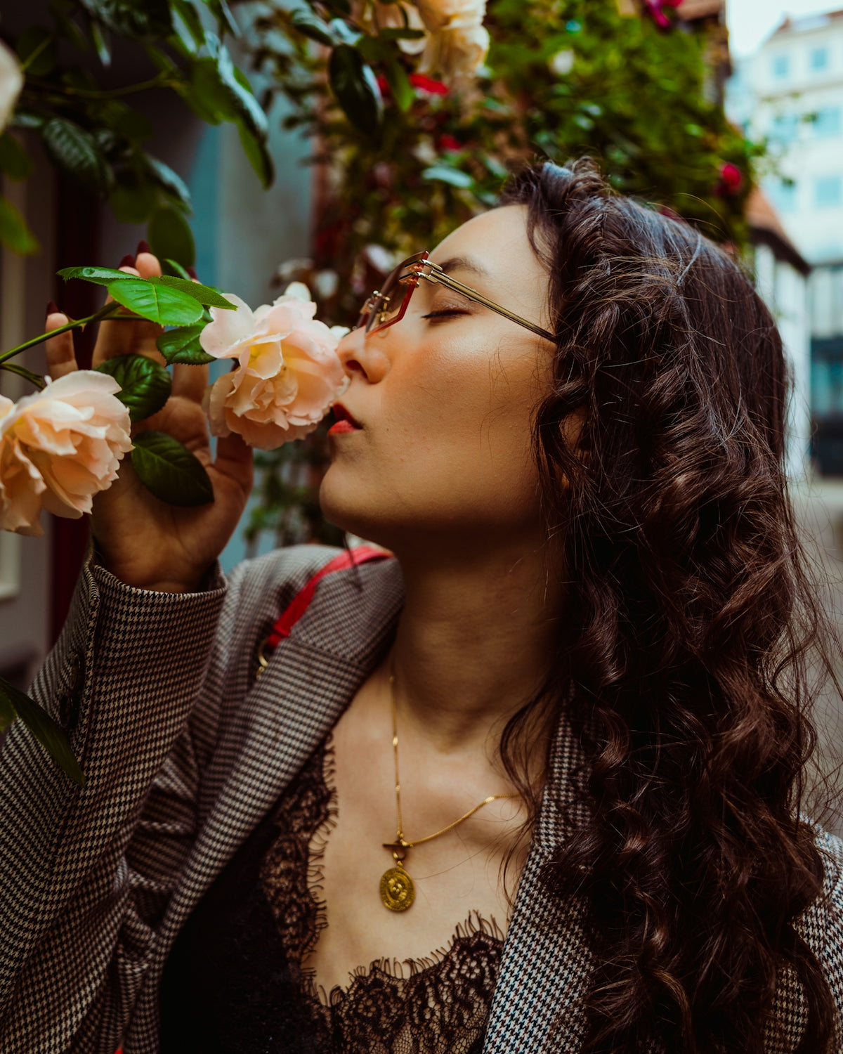 Stylish woman with glasses smelling fragrant pink roses